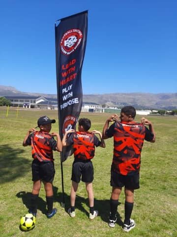 Three FS4 players holding the team flag reading Lead With Heart, Play With Purpose